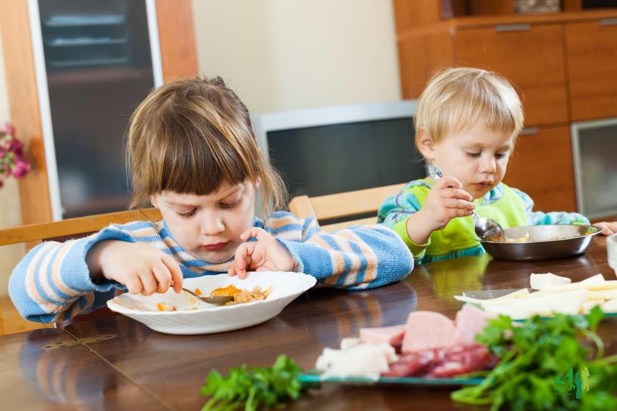 Zwei Kleinkinder sitzen am Familientisch und Essen